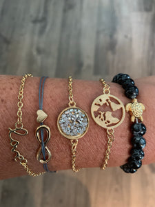 Bracelet set includes one black beaded with gold turtle stretch band, 3 gold chain with metal and jewel adornments, and one gray string with gold metal hearts, all with metal clasp closure. These can fit small to large wrists. 
